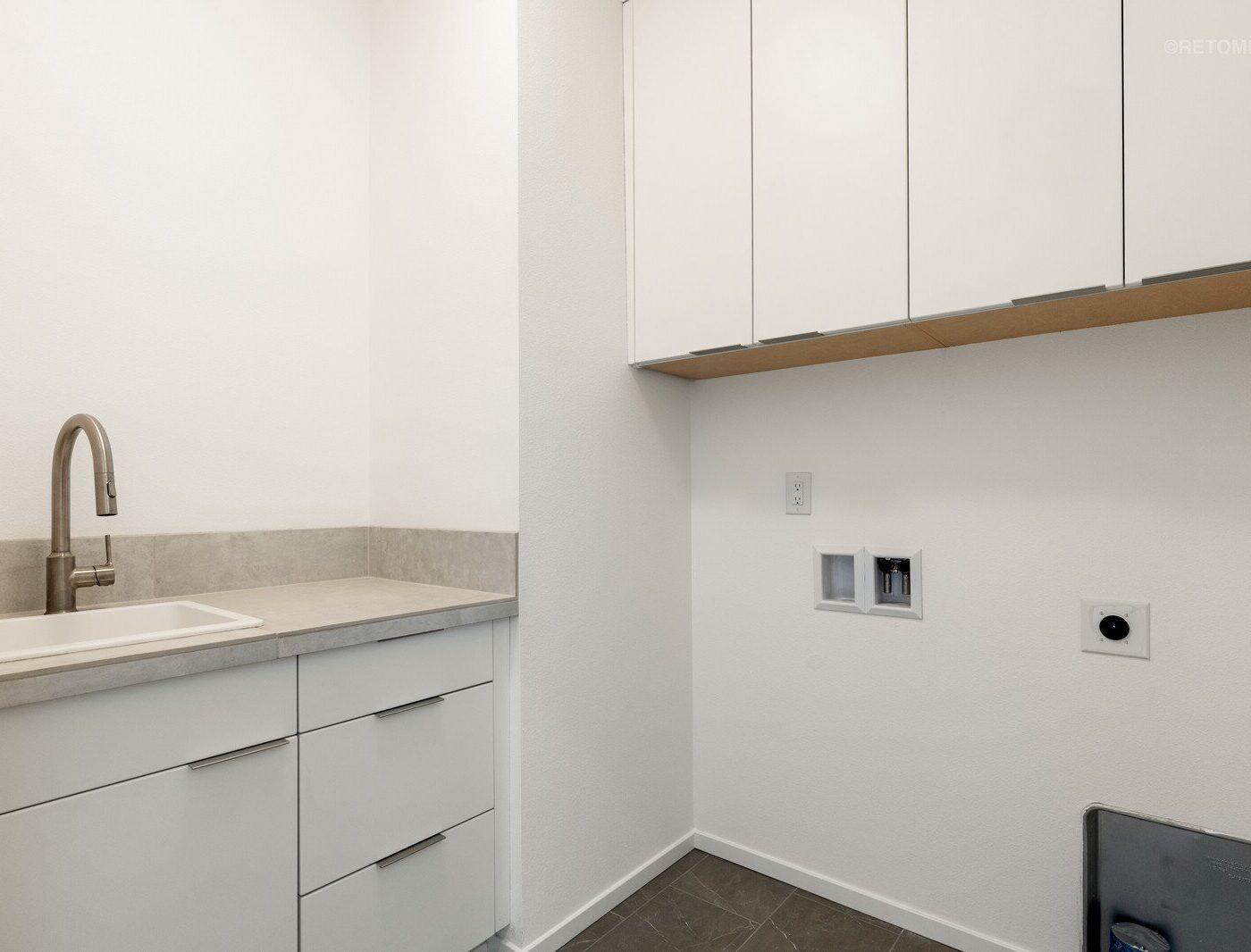 Laundry room with white cabinets, a utility sink, and wall hookups for a washer and dryer.
